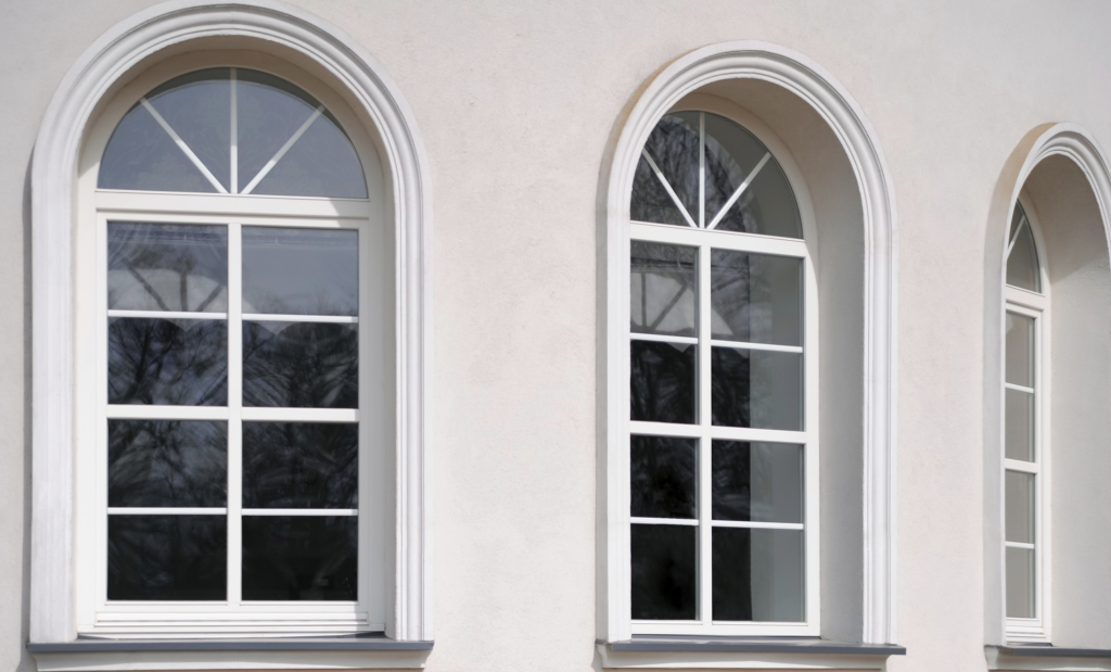 Arched windows with reflective glass in a beige building facade, showcasing classic architectural design